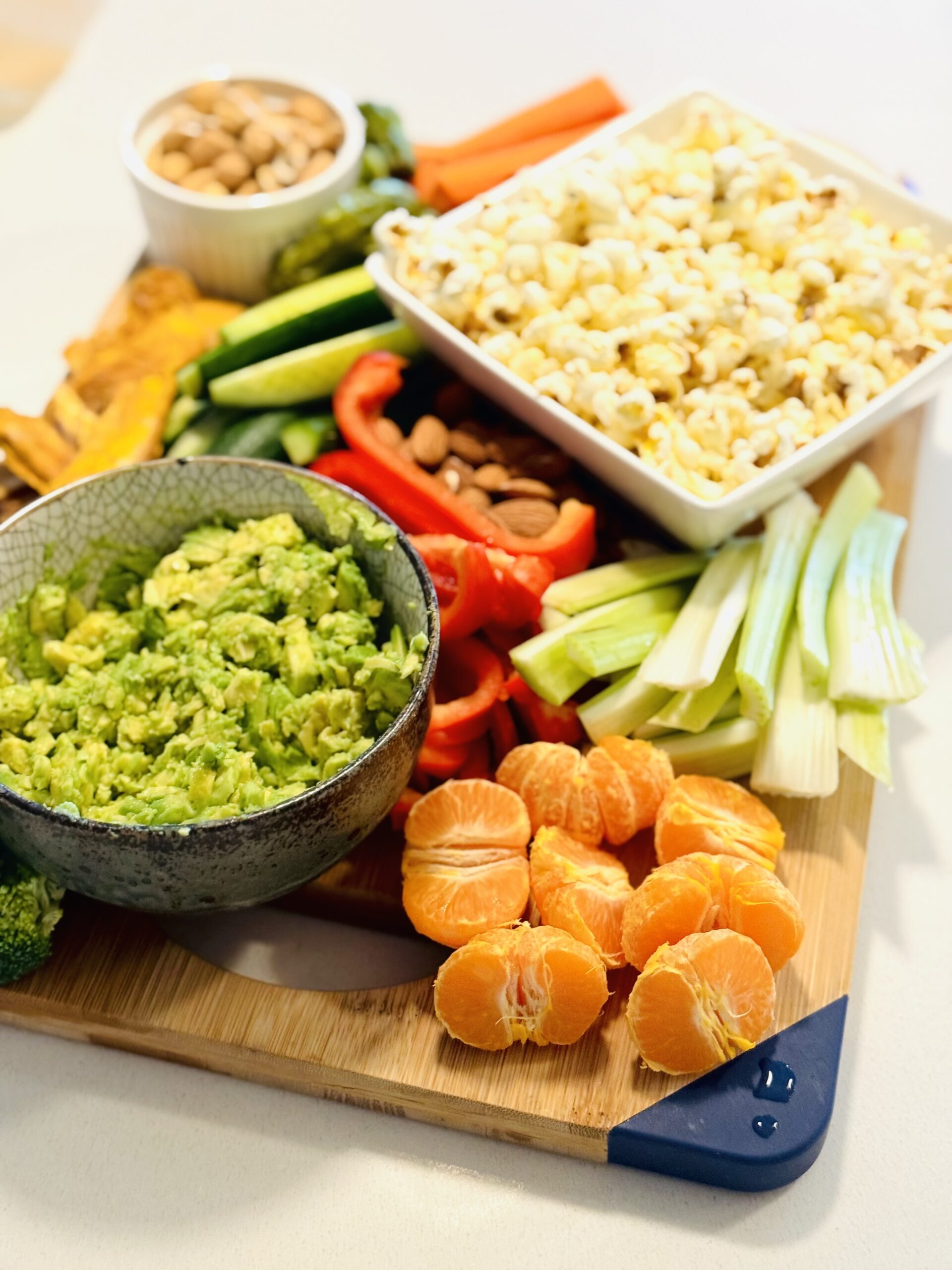 Fruits, vegetables, and popcorn on wooden cutting board